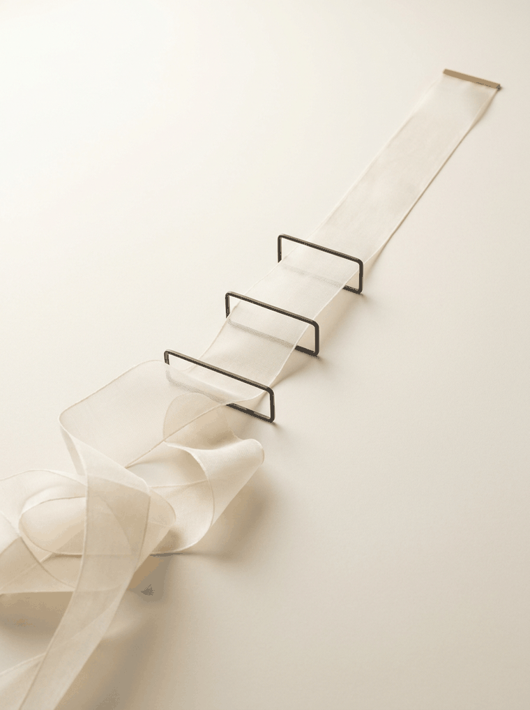 A translucent ribbon becoming aligned as it passes through a sequence of precise guide frames.